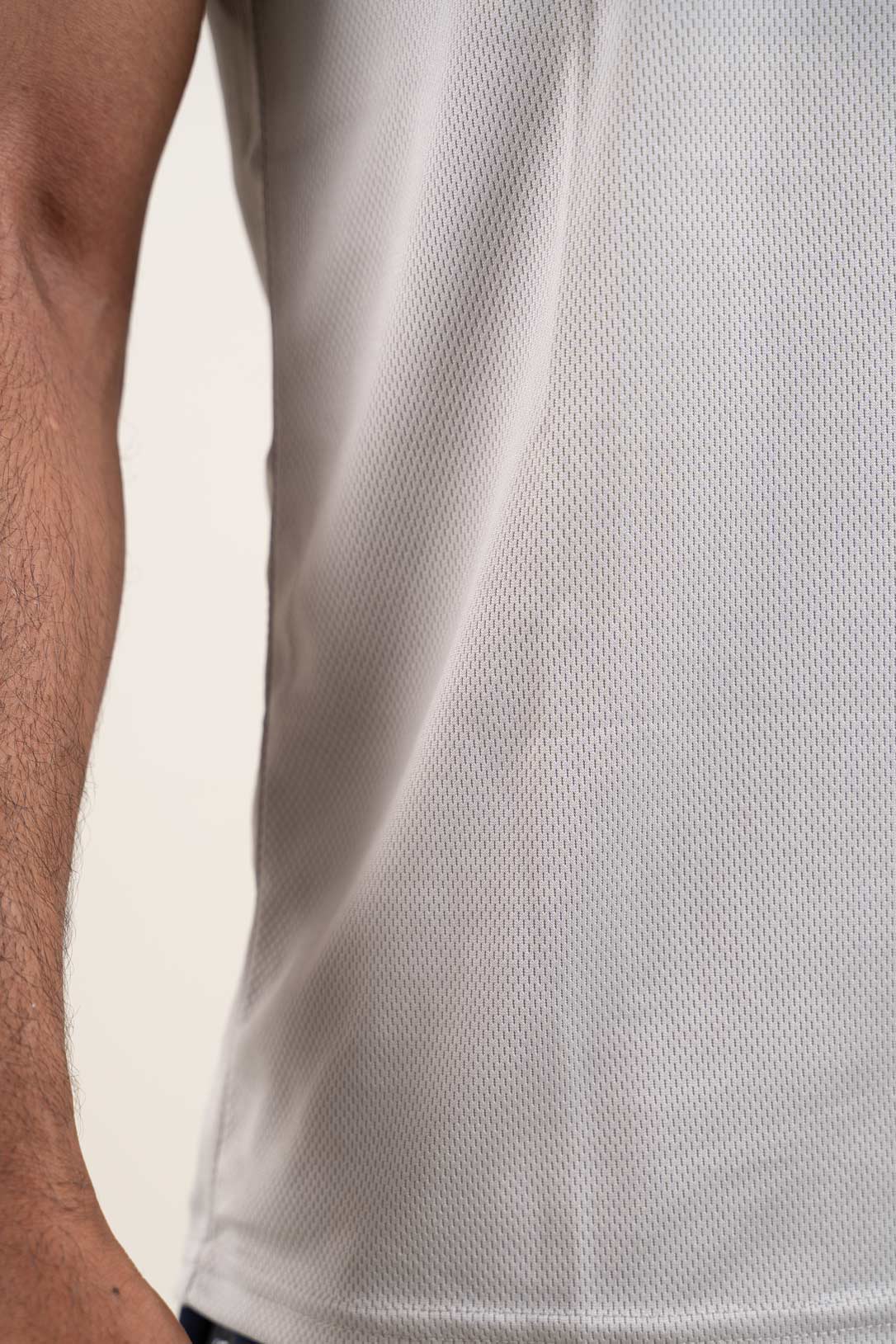 Close-up shot of the light grey polo t-shirt's fabric, revealing its breathable and moisture-wicking properties