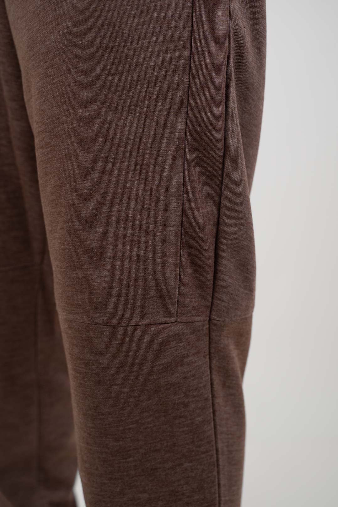 Close-up shot of the fabric of the brown joggers, revealing their soft texture and earthy color