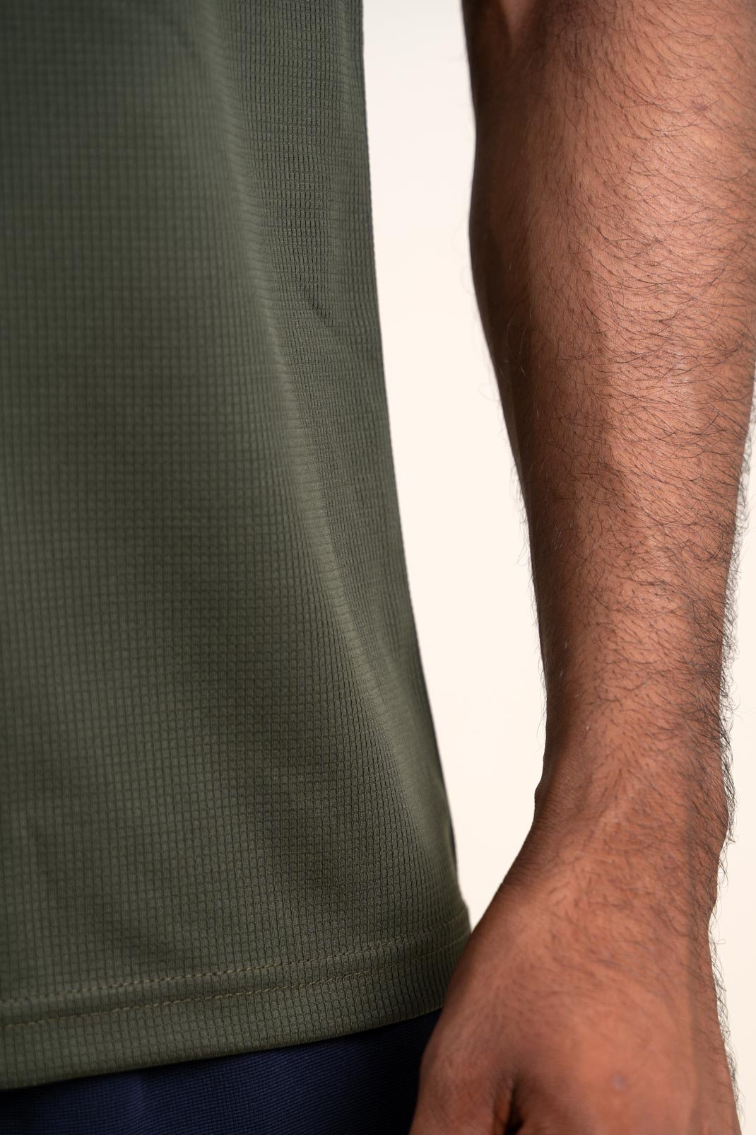 Zoomed-in view of the dark olive polo shirt's stitching and hem, showcasing its durability