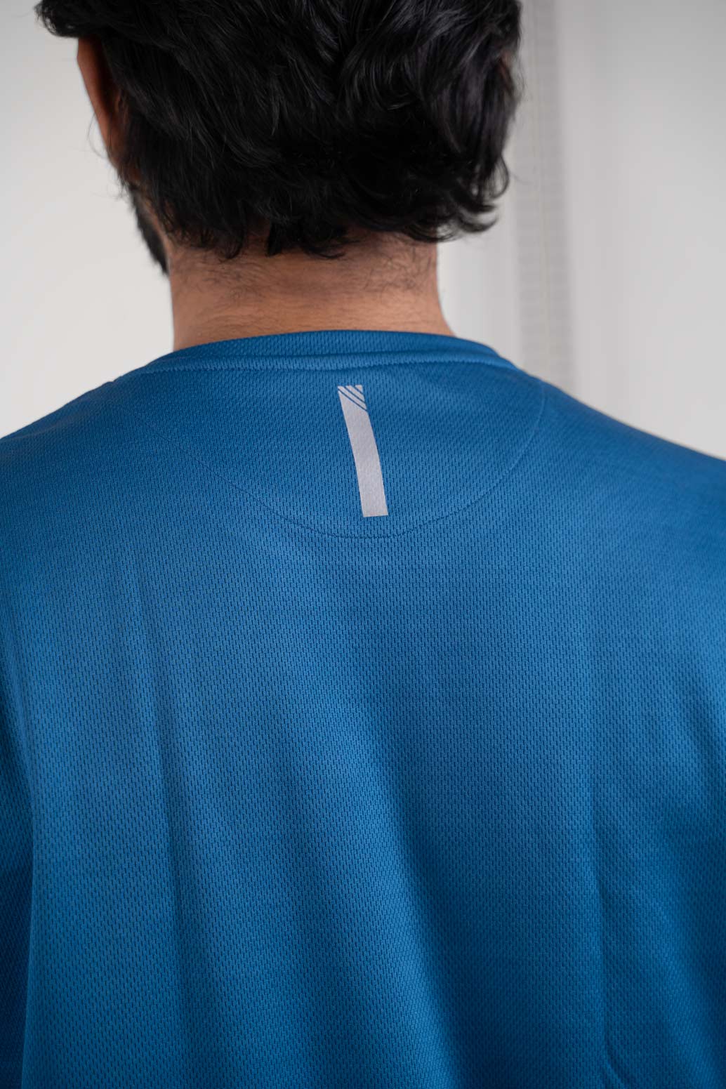 Back view of the active blue crew neck t-shirt, showcasing its minimalist and modern look