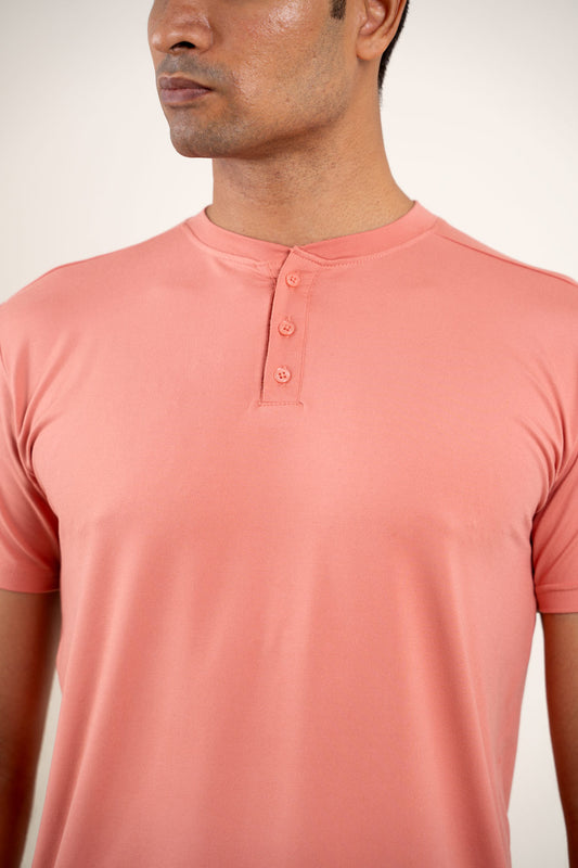 Detailed view of the buttoned neckline on the peach Henley t-shirt, emphasizing its craftsmanship