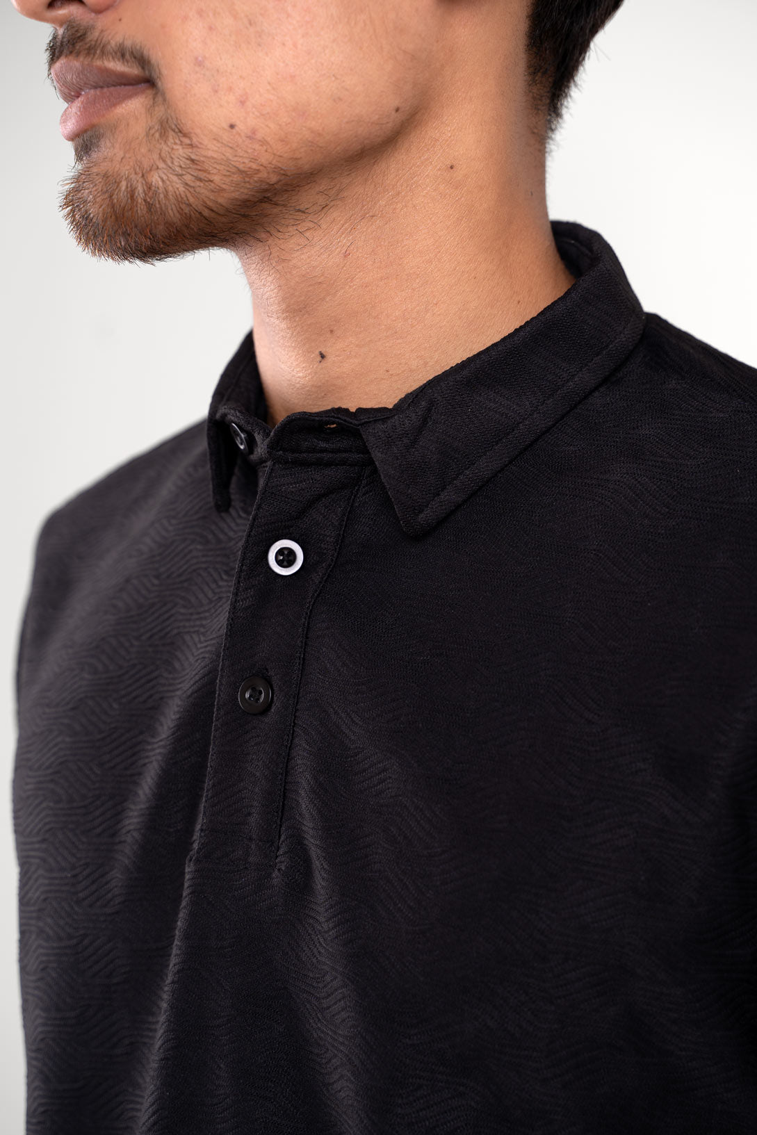 Man wearing a black polo t-shirt, front view showing buttoned collar