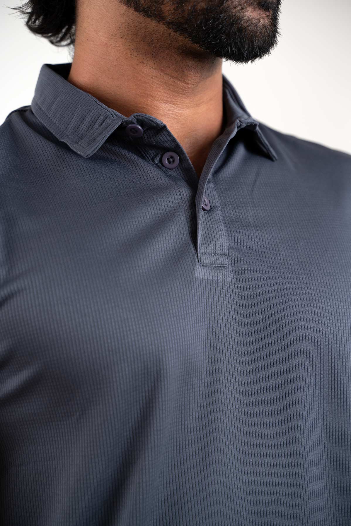 Close-up shot of the fabric of the active dark grey polo t-shirt, revealing its moisture-wicking and breathable texture