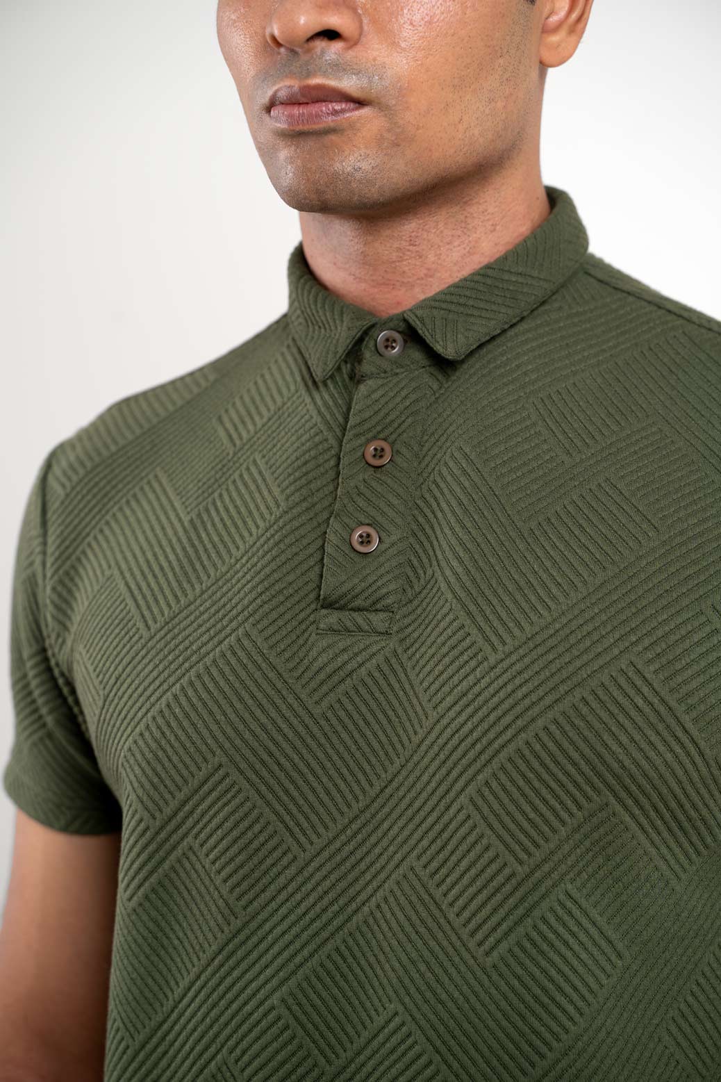 Close-up front view of man in textured green polo t-shirt showing ribbed collar and buttons