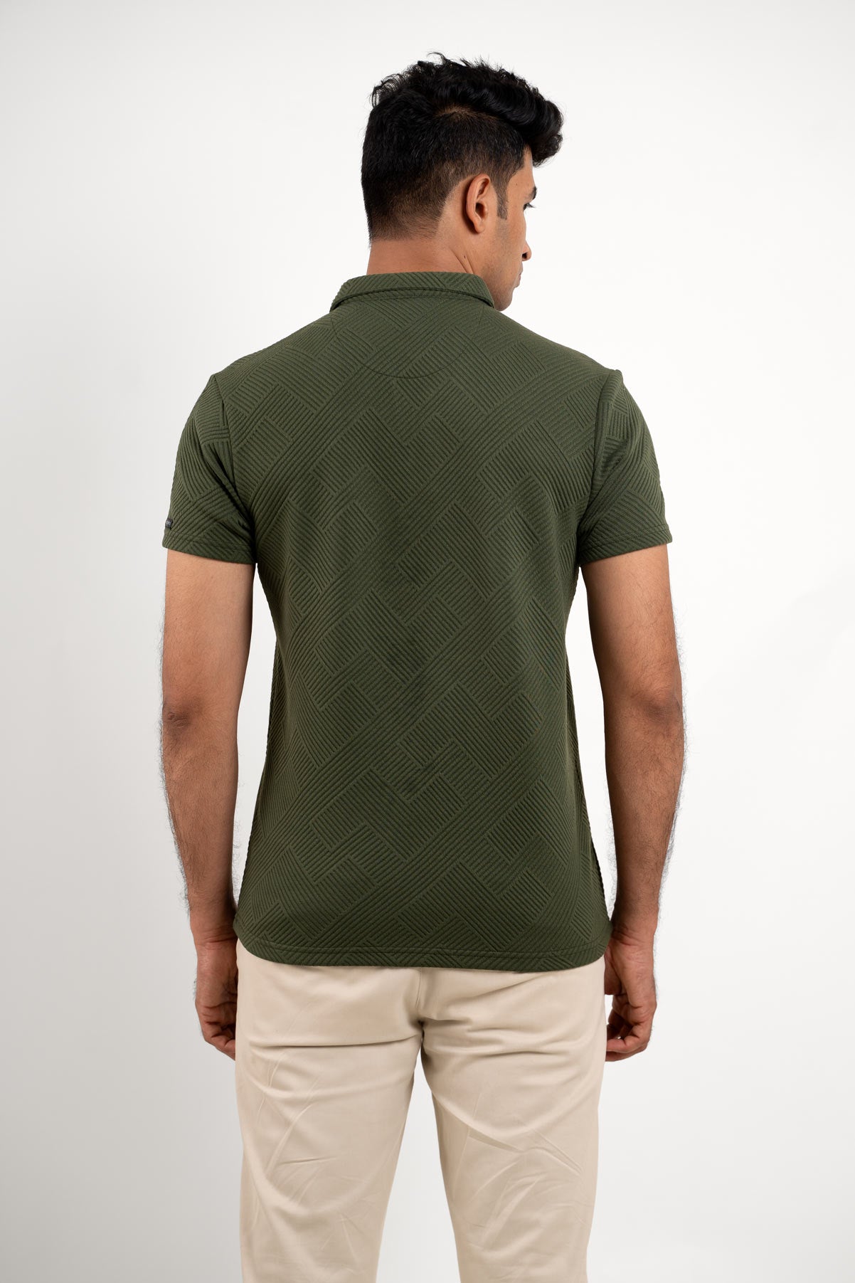 Back view of man wearing a textured green polo t-shirt, highlighting intricate fabric pattern