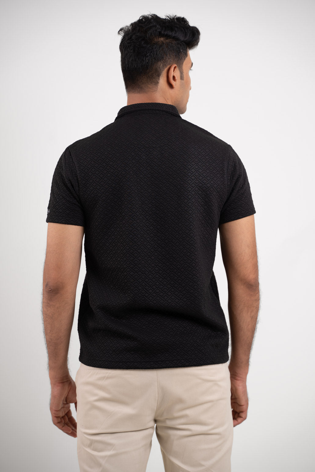 Back view of the textured black polo t-shirt, highlighting its clean and minimalist appearance