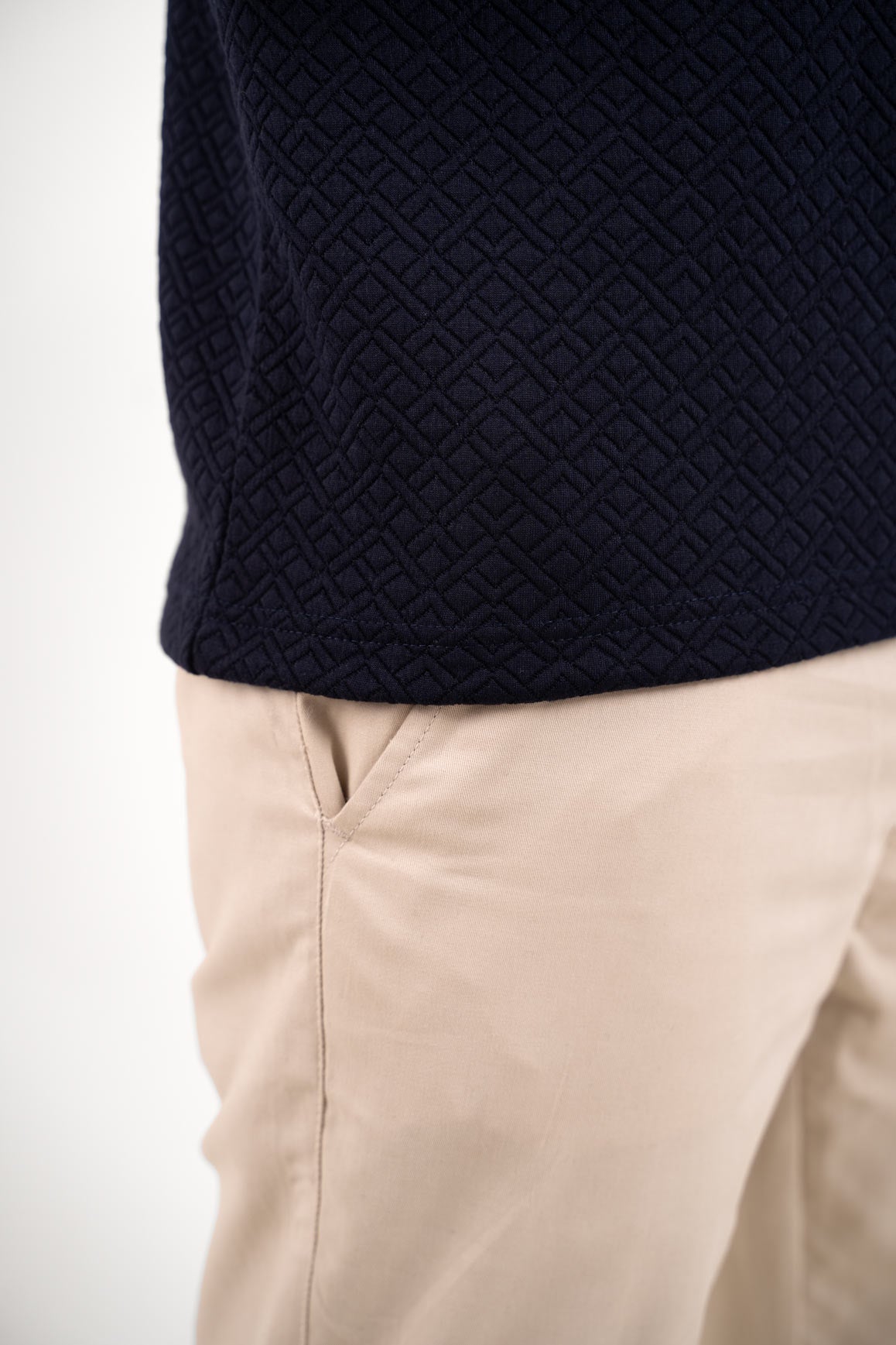 Close-up shot of the fabric texture on the navy blue polo t-shirt, revealing its intricate and stylish pattern