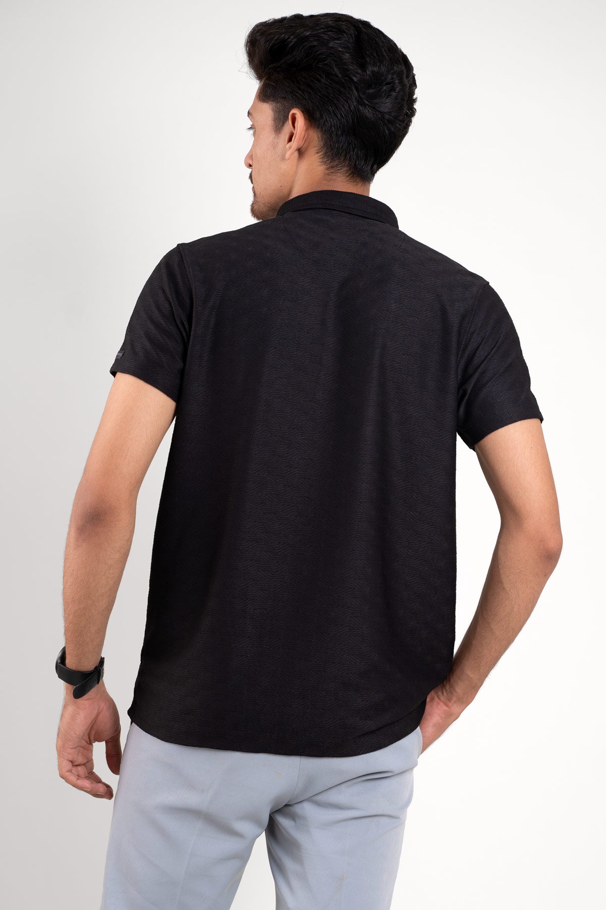 Black polo t-shirt worn by man, back view