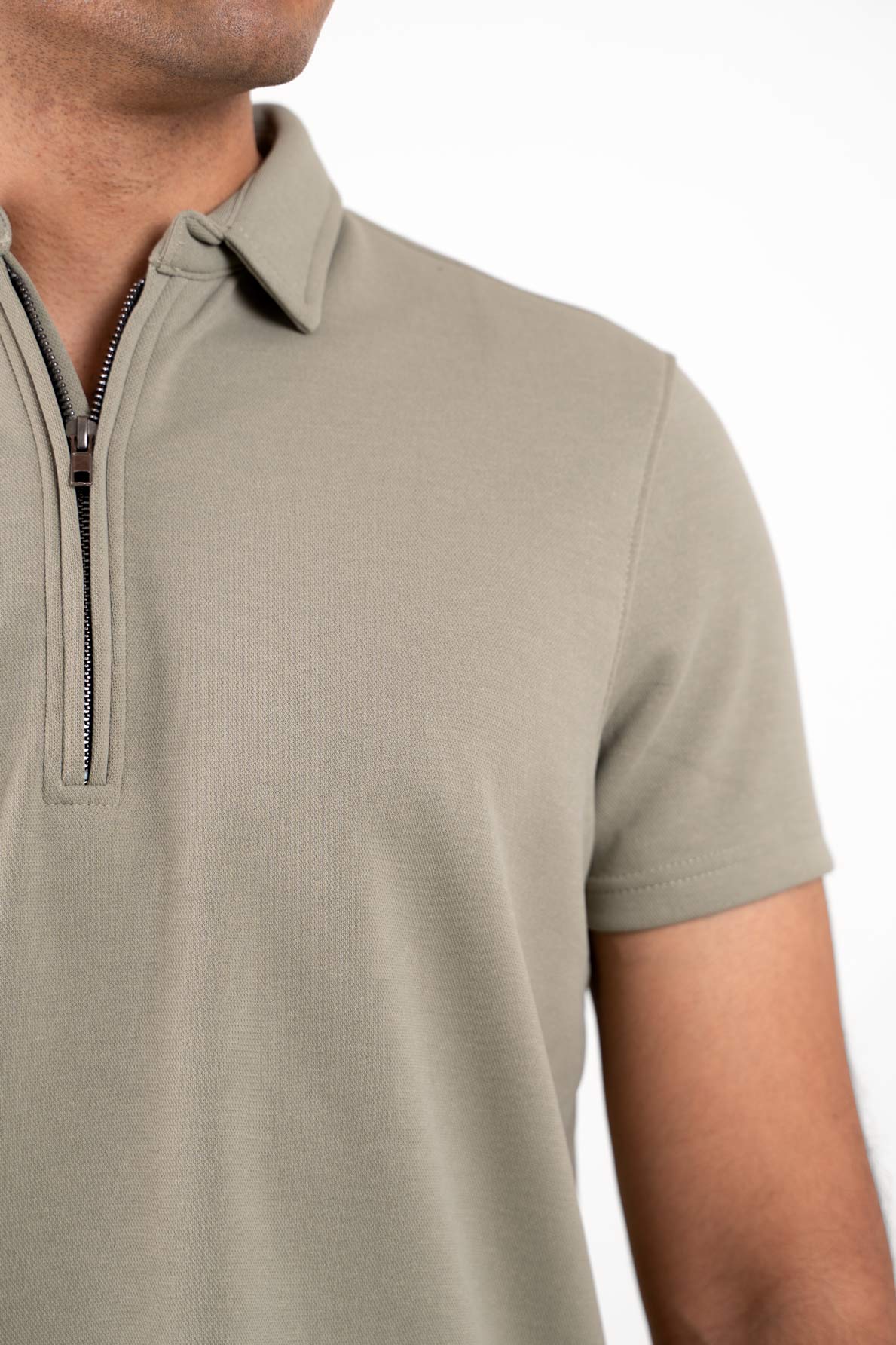 Close-up shot of the zipper collar on the light green polo shirt, showcasing its innovative design and quality