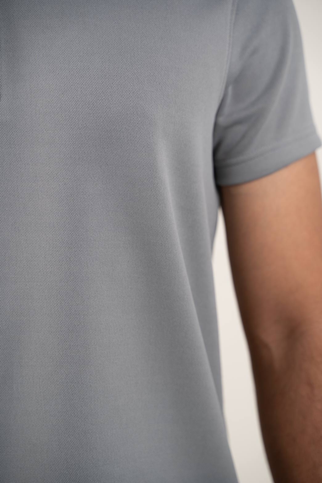 Close-up shot of the zipper collar on the grey polo shirt, showcasing its innovative and stylish design