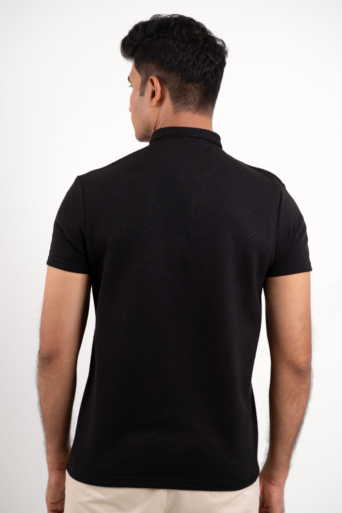 Back view of a man in a black polo tee, captured from the front, with a clear focus on the attire