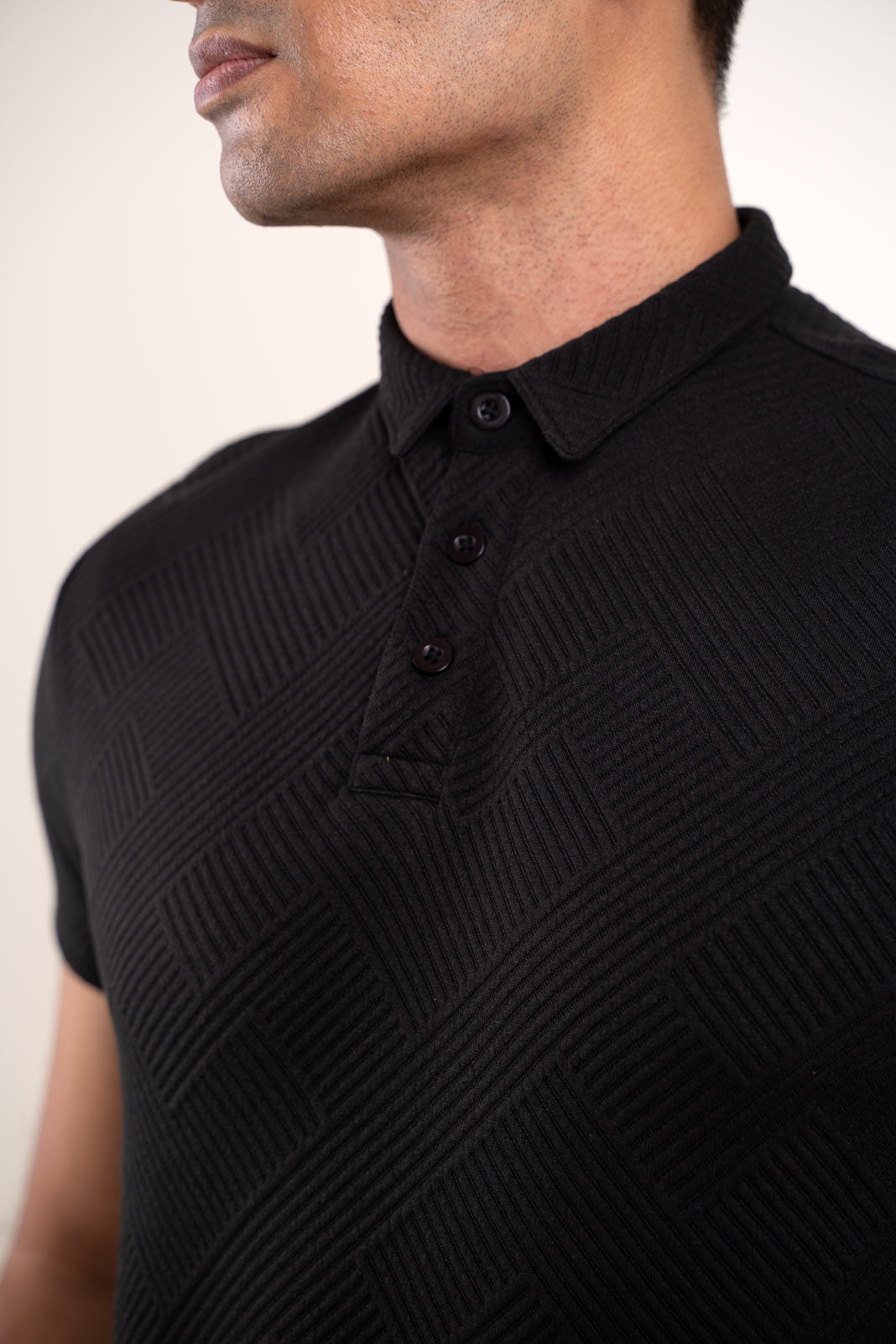 extured black polo t-shirt worn by man, front view highlighting unique fabric texture