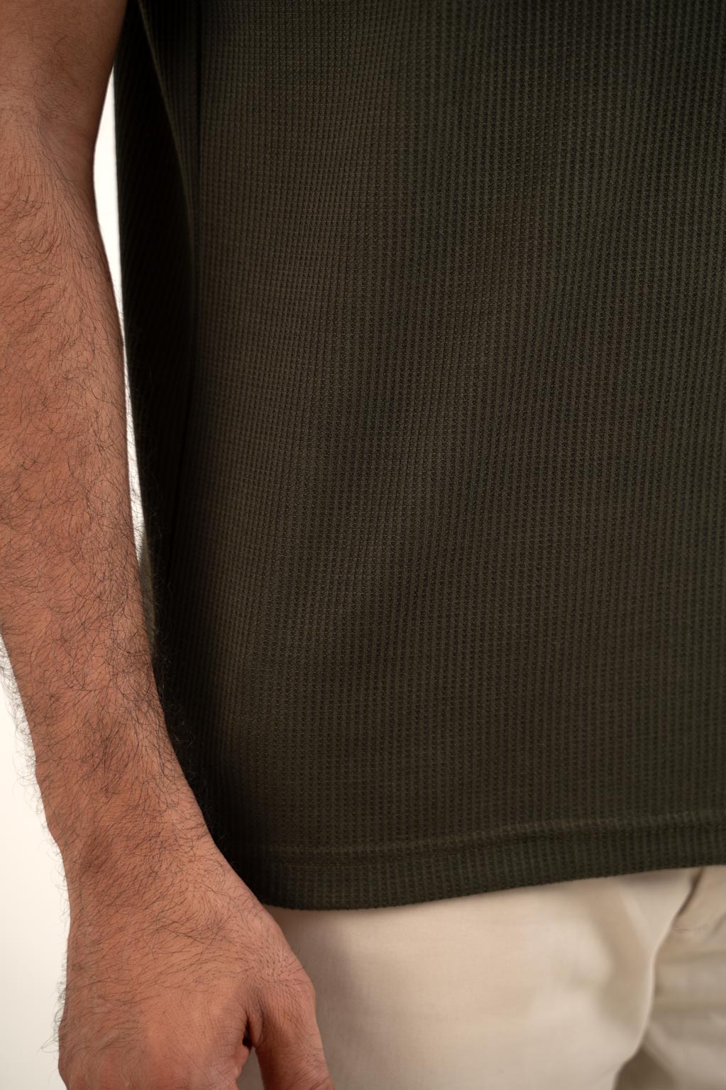 Close-up shot of the wavy fabric texture on the olive polo shirt, revealing its intricate pattern and quality