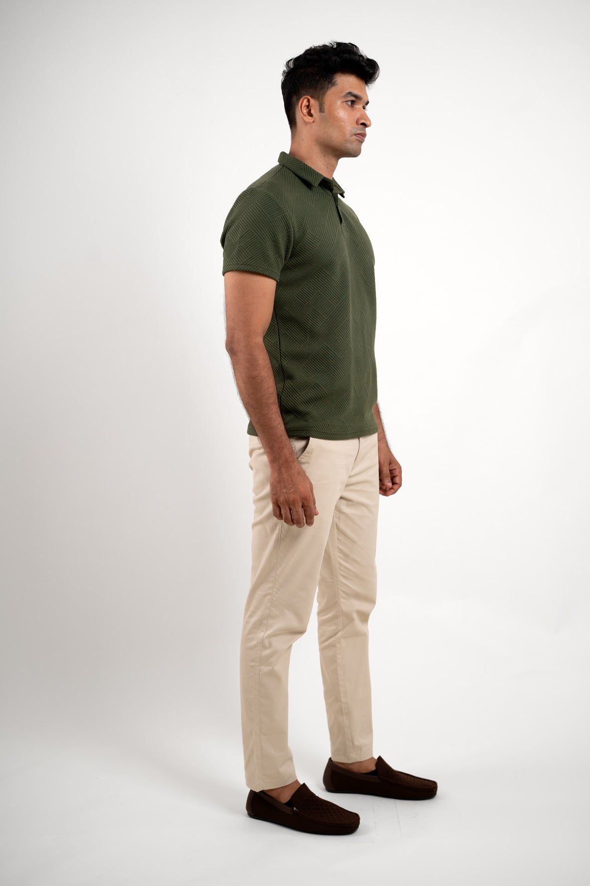 Man wearing a textured green polo t-shirt, front view emphasizing detailed weave