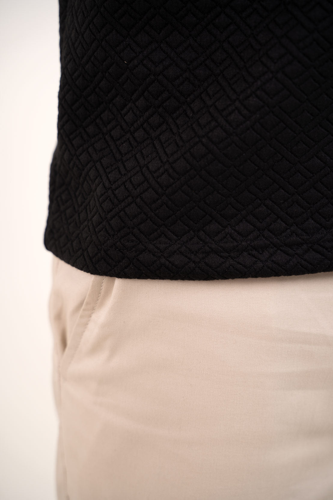 Zoomed-in view of the black polo t-shirt's hem, showcasing its precise and elegant finish