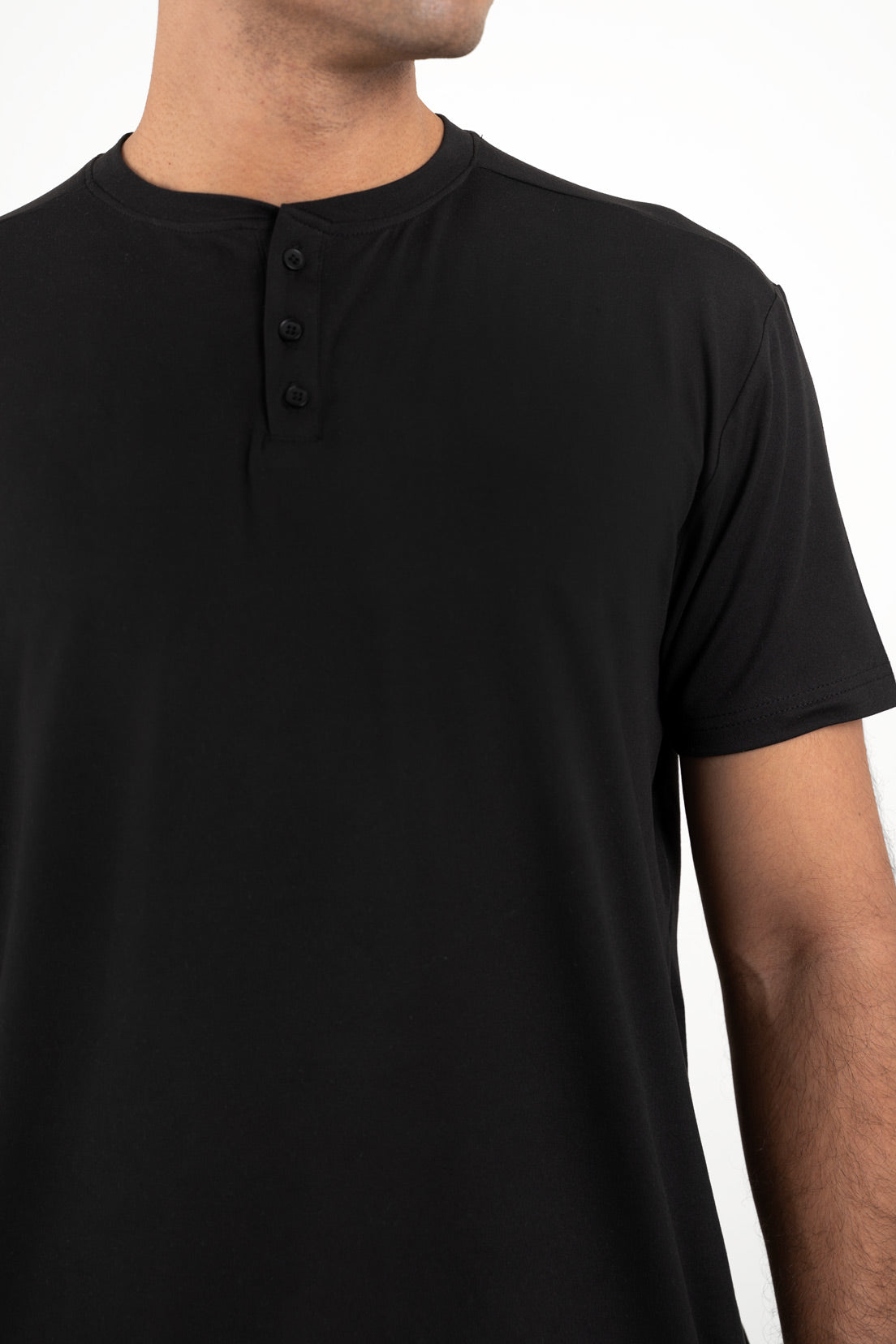 Close-up shot of the fabric of the black Henley t-shirt, revealing its smooth texture and high-quality material