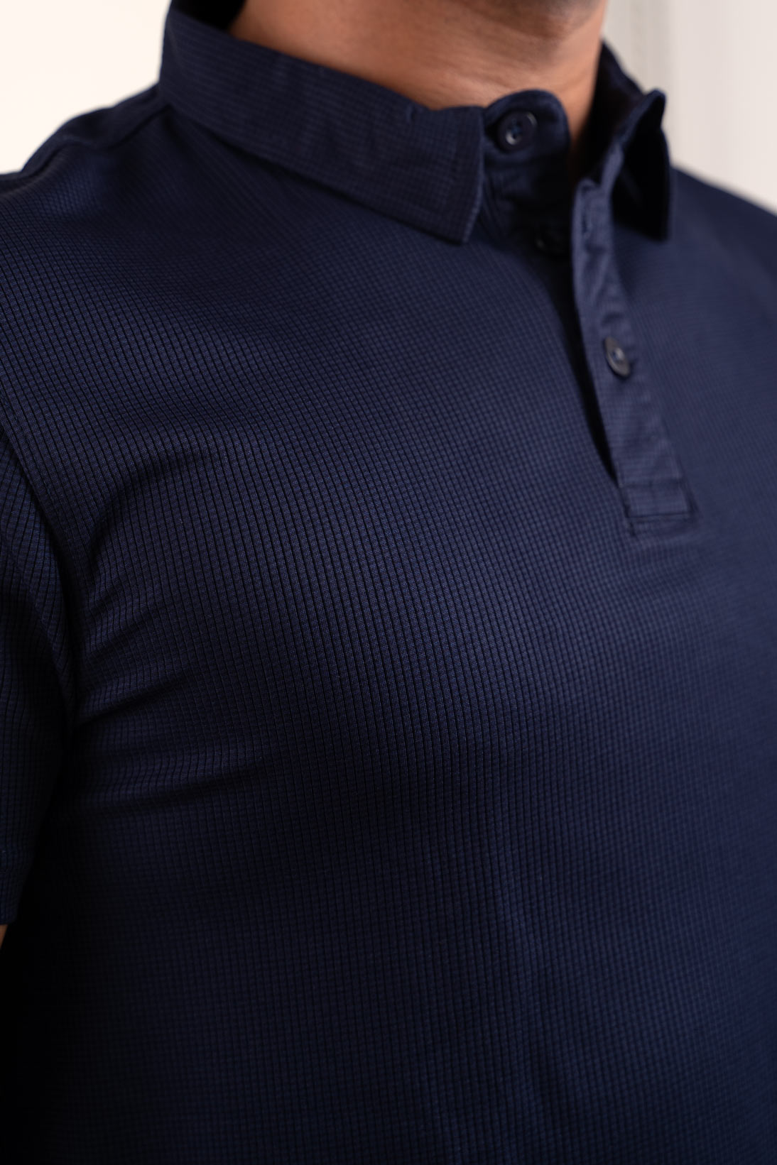 Close-up shot of the navy blue polo t-shirt's fabric, revealing its breathable and moisture-wicking properties